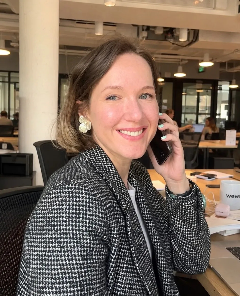 Elena Suhova, founder of What If HR, smiling on a phone call at a shared workspace